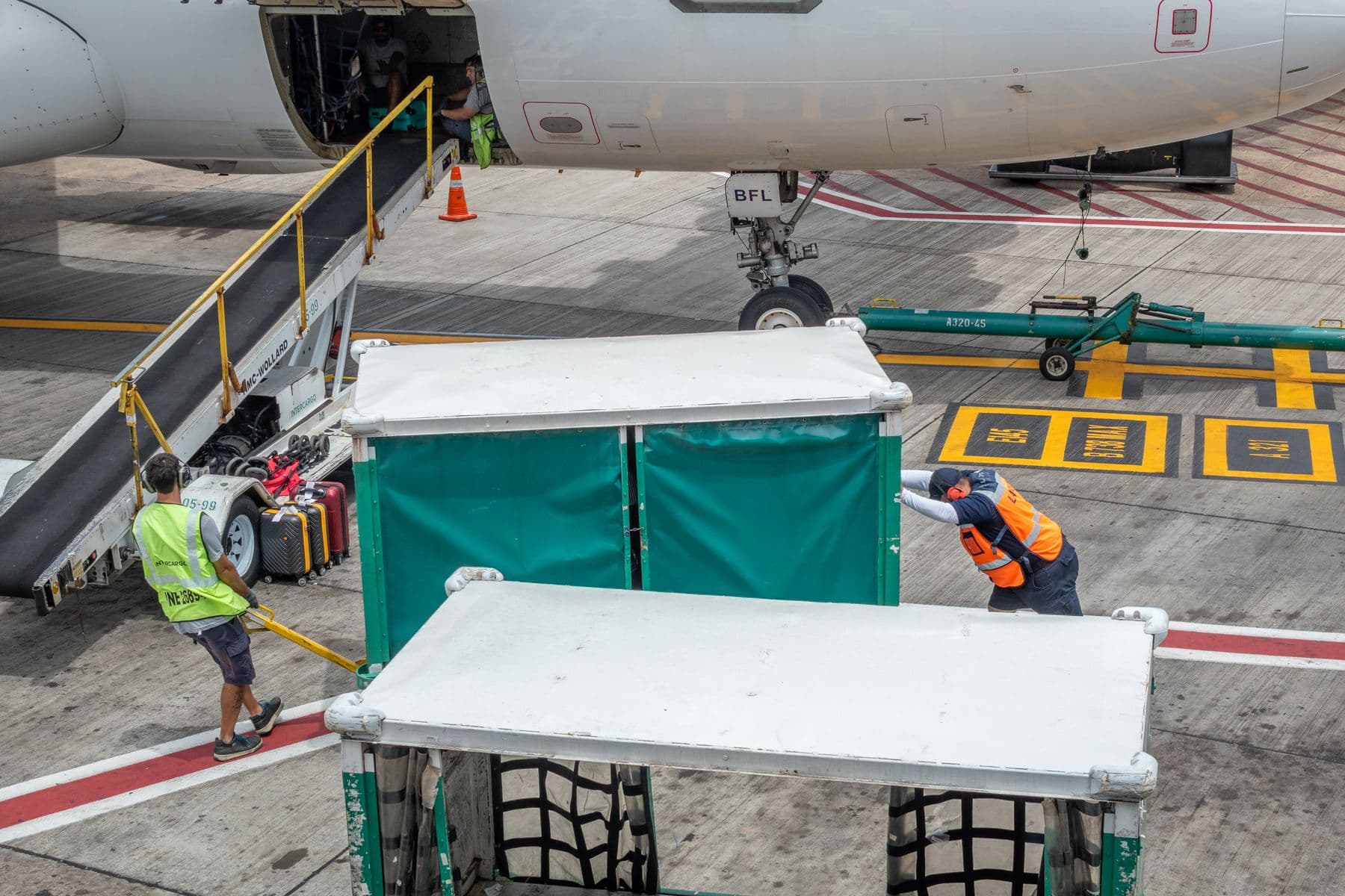Ground crew loading cargo containers beside an aircraft on the apron