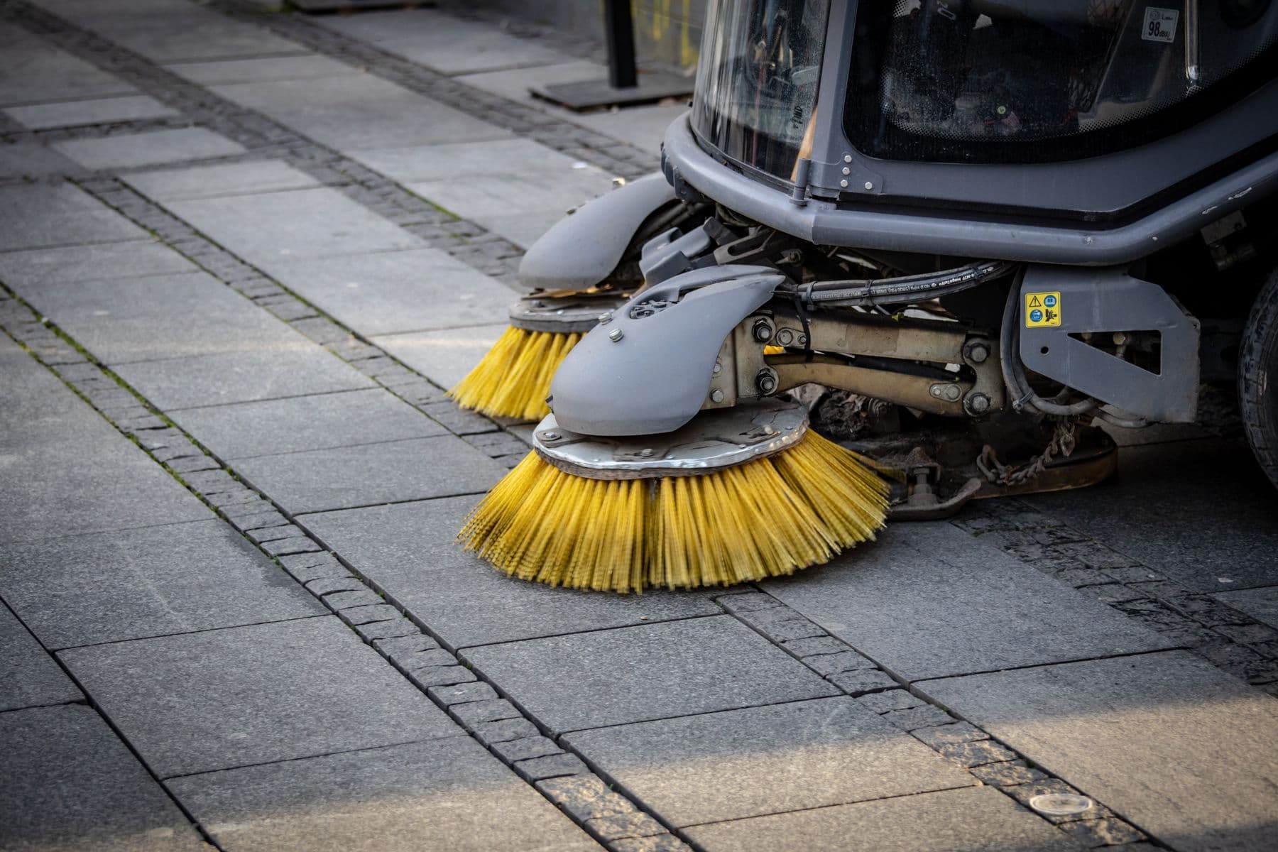 Rotating brushes of a compact street sweeper working a paved street